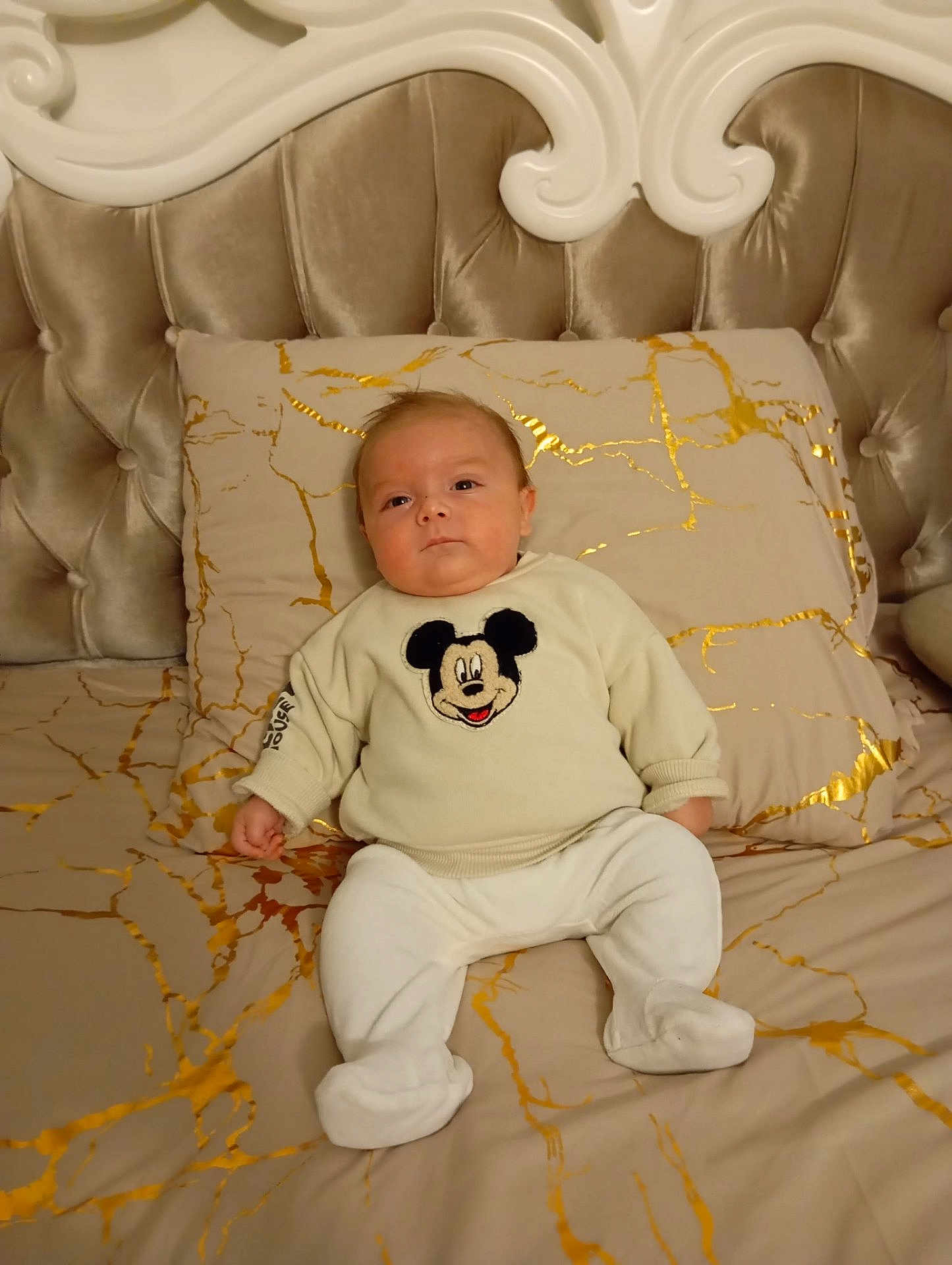 Leao a rejoint le concours — aidez-le/la à gagner de superbes lots ! baby, infant, child, bed, pillow, blanket, mickey_mouse, sweater, booties, portrait, upholstery, headboard, tufted, indoors, cozy, neutral_tones, cute, relaxed, photography, bedding