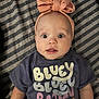 Laci Joy joined the competition — help win amazing prizes! apparel, baby, bluey, bow, cartoon, child, clothing, cute, expression, eyes, face, headband, indoor, infant, lying_down, mouth, person, portrait, shirt, striped_blanket