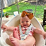 arm, baby, bow, child, clothing, fence, flower_pot, foot, garden, grass, happy, infant, outdoor, plants, playtime, seat, smile, straps, sunlight, swing