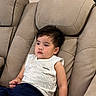 child, toddler, portrait, sitting, recliner, chair, indoors, home, living_room, face, dark_hair, looking_away, calm, clothing, shirt, shorts, barefoot, furniture, relaxed, photography