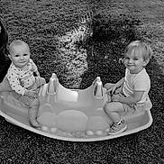 Jimmy a rejoint le concours — aidez-le/la à gagner de superbes lots ! child, baby, toddler, woman, outdoor, grass, playground, rocker, toy, smile, happy, person, sitting, footwear, shirt, shorts, glasses, hand, face, nature