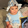 baby, child, infant, smiling, blue_outfit, floral_pattern, bonnet, bed, blanket, phone, reflection, closeup, cute, indoors, person, sitting, white_sandals, bracelet, soft_lighting, portrait