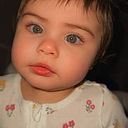 Aisha joined the competition — help win amazing prizes! toddler, child, face, portrait, close_up, baby_clothing, floral_pattern, onesie, cute, curious, green_eyes, hair_tufts, indoor, soft_lighting, young_child, person, infant, skin, eyelashes, nose
