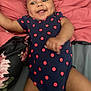 baby, infant, smile, polka_dot, onesie, bed, pillow, pink, gray, happy, dimple, skin, face, arm, leg, clothing, lying_down, cute, child, person