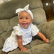 Kaizlee is registered to the contest to win money with this photo: baby, child, smiling, happy, crawling, headband, bow, dress, white_clothing, floral_pattern, bracelet, armchair, green_furniture, indoor, home, cute, person, portrait, infant, young_child