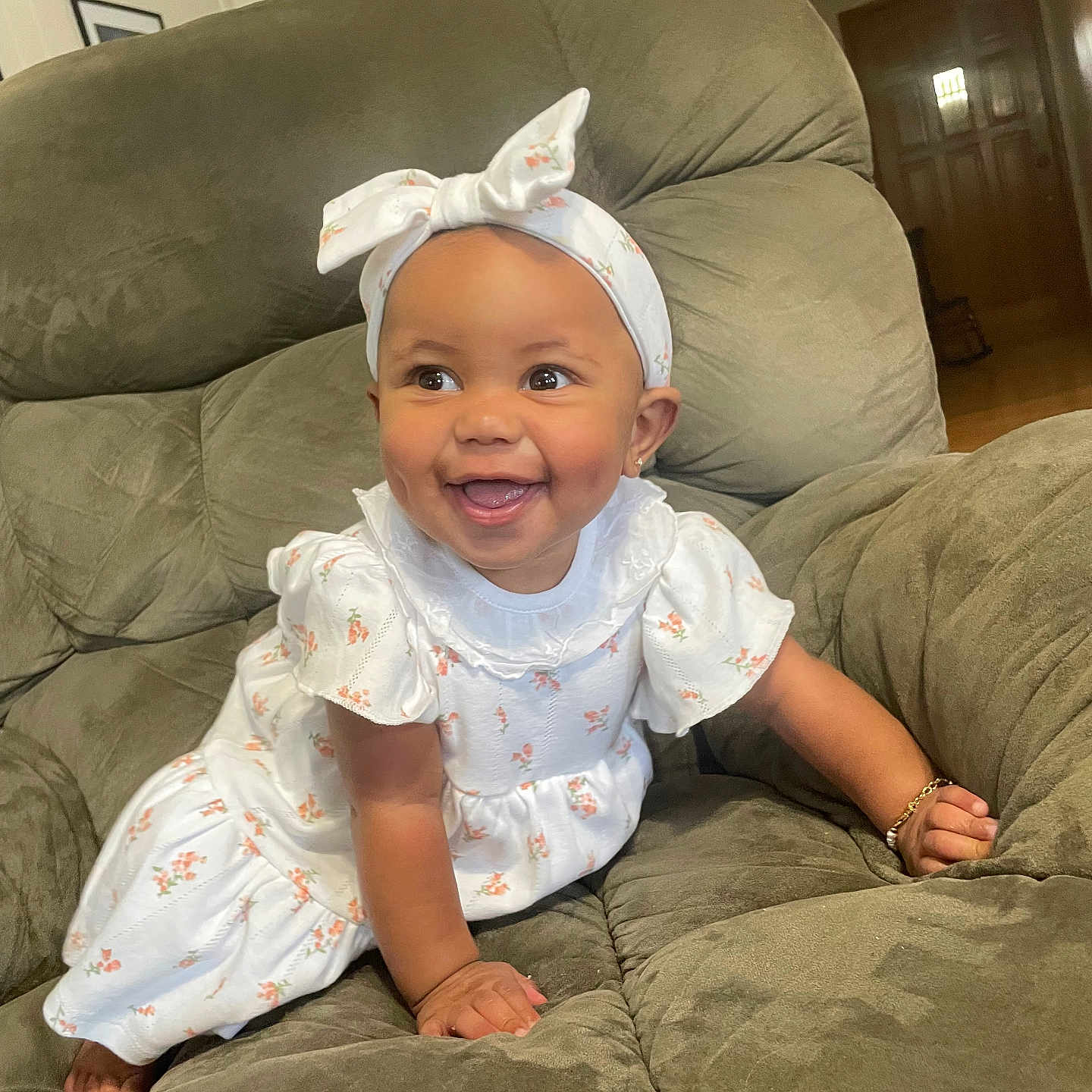 Kaizlee is registered to the contest to win money with this photo: armchair, baby, bow, bracelet, child, crawling, cute, dress, floral_pattern, green_furniture, happy, headband, home, indoor, infant, person, portrait, smiling, white_clothing, young_child