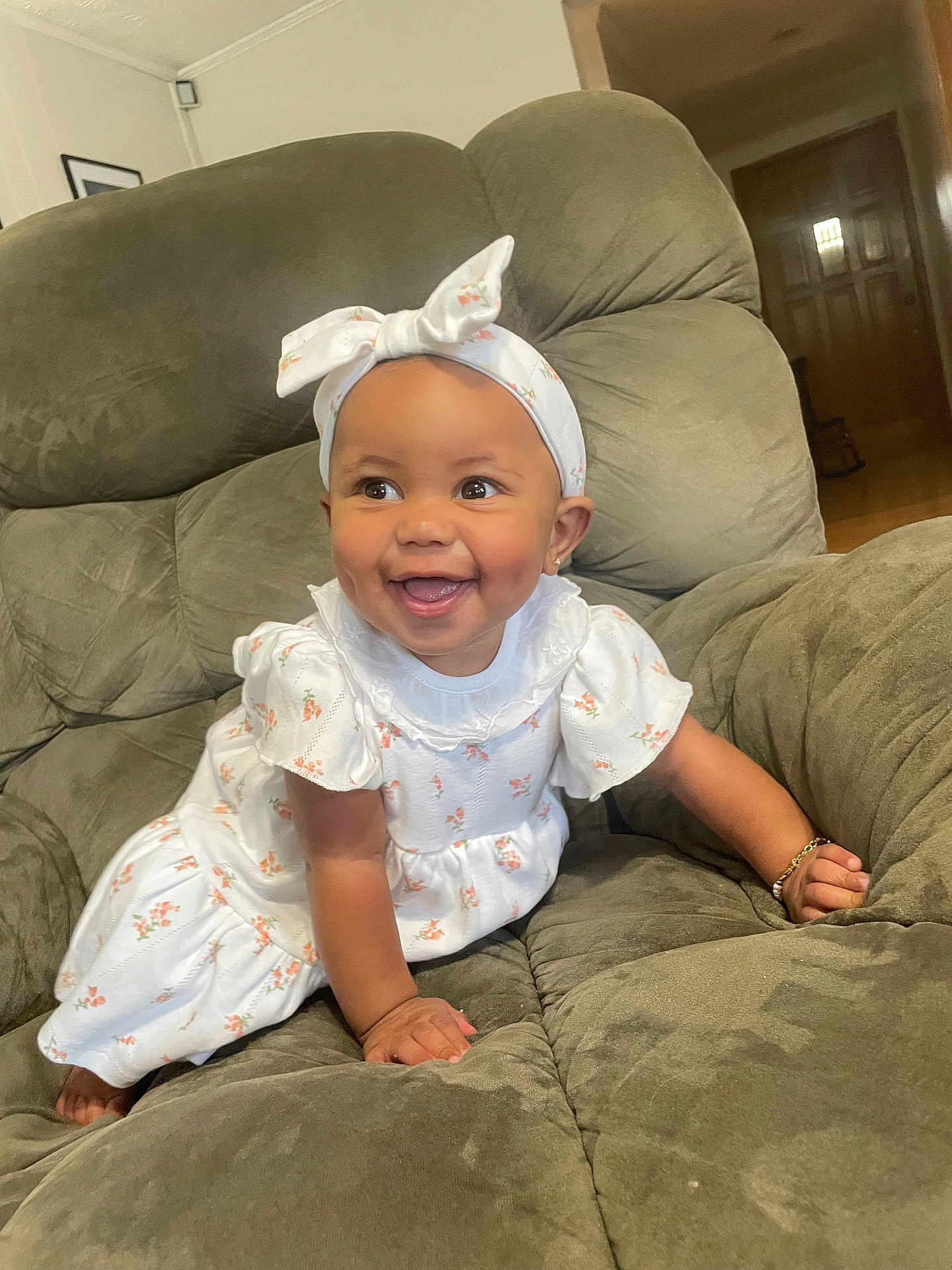 Kaizlee is registered to the contest to win money with this photo: baby, child, smiling, happy, crawling, headband, bow, dress, white_clothing, floral_pattern, bracelet, armchair, green_furniture, indoor, home, cute, person, portrait, infant, young_child
