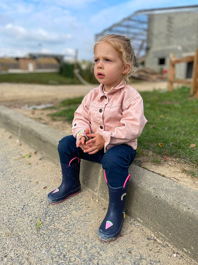 Maëlle a rejoint le concours — aidez-le/la à gagner de superbes lots ! child, cloud, electric_blue, fun, grass, happy, human_leg, leg, leisure, people_in_nature, person, recreation, road_surface, shoe, sitting, sky, sleeve, street_fashion, summer, toddler