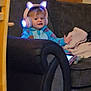 toddler, child, headphones, glowing, cat_ears, blue_onesie, couch, tablet, blanket, indoor, furniture, wooden_door, chair, cozy, technology, person, seated, expression, living_room, home