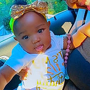 Eliana is registered to the contest to win money with this photo: baby, bow, car_interior, child, clothing, cute, face, greenery, hand, happy, headband, nature_outside, person, portrait, seat, smile, socks, sunlight, window, yellow