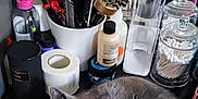 Bonyta participe au concours pour gagner de l'argent avec cette photo : kitten, gray_cat, cat, pet, animal, fur, curious, lying_down, black_surface, toiletries, brushes, cotton_swabs, bottles, container, grooming_tools, domestic, indoor, closeup, relaxed, tabletop