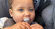 Sylver joined the competition — help win amazing prizes! toddler, child, baby, water_bottle, car_seat, curly_hair, blue_eyes, hands, face, seatbelt, gray, drinking_water, plastic_bottle, young_child, portrait, indoor, close_up, person, cute, infant