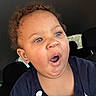 baby, child, infant, portrait, face, eyes, wide_eyed, surprised, open_mouth, expression, curly_hair, earring, clothing, shirt, car, car_interior, seat, close_up, indoor, photography