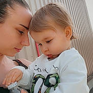 Tiago a rejoint le concours — aidez-le/la à gagner de superbes lots ! affection, brown_hair, building_wall, candid, casual_clothing, child, closeup, daylight, face, holding, intense_gaze, interaction, outdoor, profile, skin, toddler, water_bottle, white_sweater, woman, young