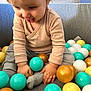 Tiago a rejoint le concours — aidez-le/la à gagner de superbes lots ! baby, ball_pit, beige_shirt, child, clothing, colorful, cozy, feet, fun, grey_pants, hands, happy, indoor, plastic_balls, playing, playtime, sitting, smiling, soft_lighting, toddler