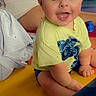 baby, child, smiling, yellow_shirt, sitting, indoor, person, happy, playmat, cute, face, portrait, clothing, toy, expression, young, infant, casual, love_text, black_heart