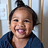 baby, blue_shirt, button, child, closeup, clothing, cute, expression, eyes, face, hair, happy, indoor, person, portrait, skin, smile, tongue_out, topknot, young_child