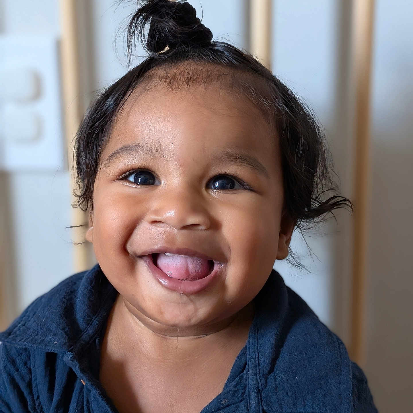 Maayoan is registered to the contest to win money with this photo: baby, blue_shirt, button, child, closeup, clothing, cute, expression, eyes, face, hair, happy, indoor, person, portrait, skin, smile, tongue_out, topknot, young_child