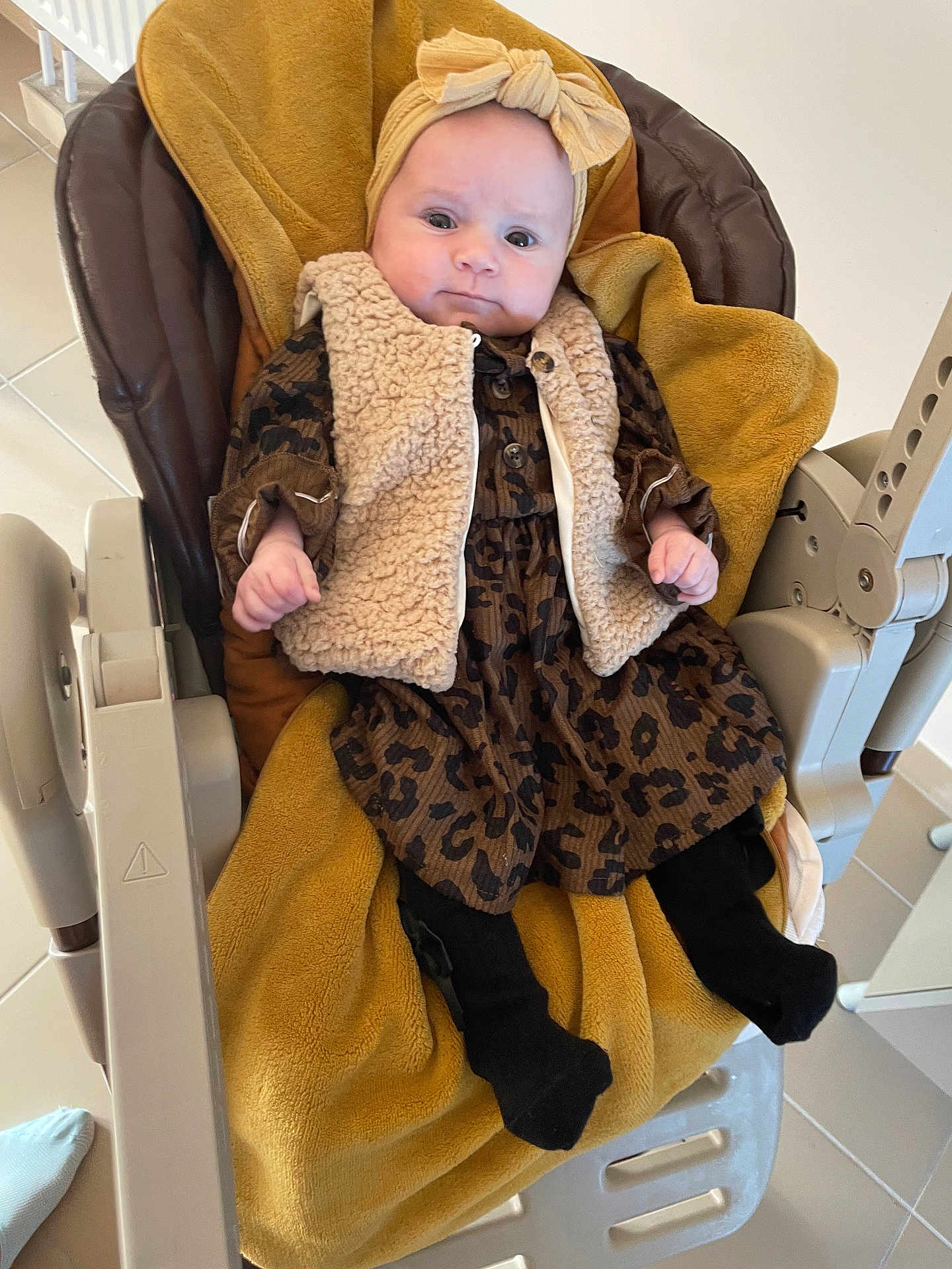 Lyna a rejoint le concours — aidez-le/la à gagner de superbes lots ! baby, infant, child, baby_chair, blanket, headband, bow, vest, dress, leopard_print, black_tights, indoors, floor_tiles, cushion, furniture, cute, portrait, young_child, clothing, seated