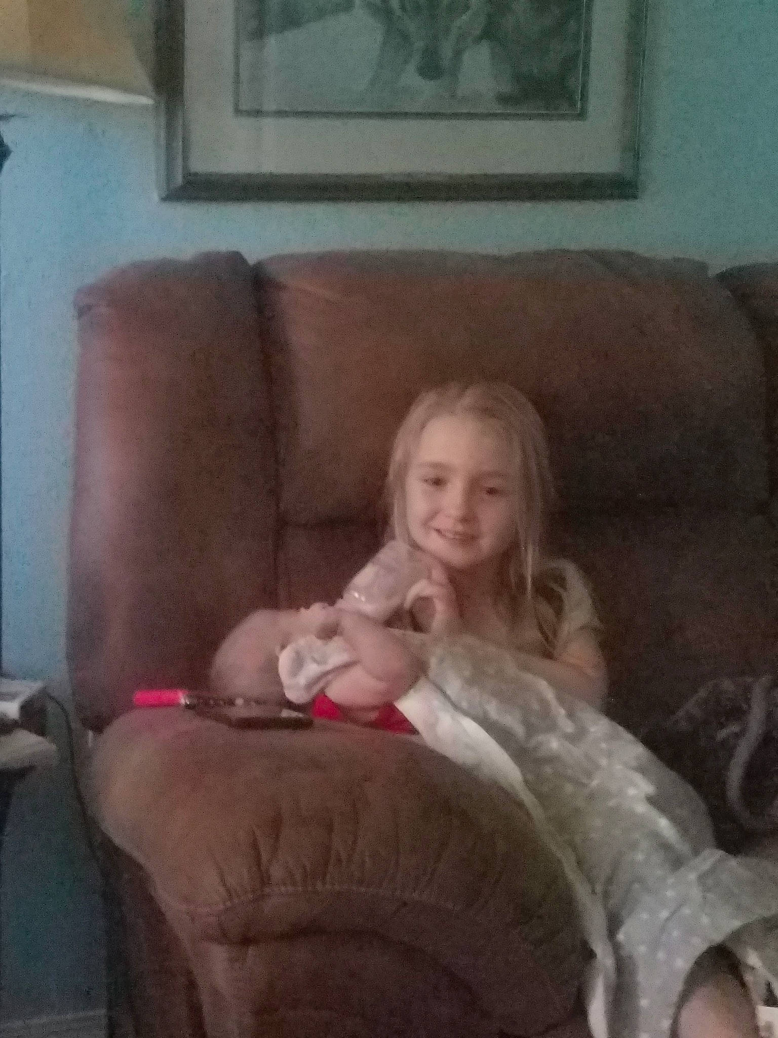 Dixie is registered to the contest to win money with this photo: blond, chair, child, couch, finger, furniture, joy, leg, mouth, person, selfie, sitting, thigh, thumb, toddler