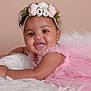adorable, baby, child, closeup, cute, earrings, face, flower_headband, fur, hand, happy, infant, lying_down, pink_dress, portrait, skin, smile, soft_texture, studio, tongue