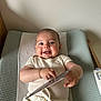 Ethan a rejoint le concours — aidez-le/la à gagner de superbes lots ! baby, smiling, infant, changing_pad, clothing, shorts, tshirt, hand, face, skin, indoor, light, texture, object, happy, lying_down, baby_care, child, person, room