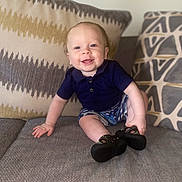 Jordan joined the competition — help win amazing prizes! baby, child, smiling, couch, pillow, clothing, shorts, shirt, footwear, indoor, portrait, happy, infant, sitting, face, furniture, home, cute, drool, patterned_pillow
