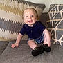 baby, child, smiling, couch, pillow, clothing, shorts, shirt, footwear, indoor, portrait, happy, infant, sitting, face, furniture, home, cute, drool, patterned_pillow