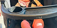 Laynie joined the competition — help win amazing prizes! baby, stroller, infant, child, pink_clothing, blue_eyes, feet, sitting, black_stroller, sunlight, curious_expression, seatbelt, outdoor, baby_bib, child_in_stroller, toddler, person, footwearless, daylight, baby_jogger