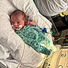 newborn, baby, hospital, incubator, medical_tubes, medical_equipment, green_onesie, floral_pattern, baby_face, baby_clothing, patient, healthcare, monitor, hospital_bed, infant, medical_tape, cute, lying_down, premature_baby, pediatric