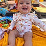 baby, smiling, toddler, orange_towel, outdoor, sunny, poolside, lounge_chair, clothing, happy, person, child, summer, daylight, recreation, relaxation, seat, cute, playful, infant