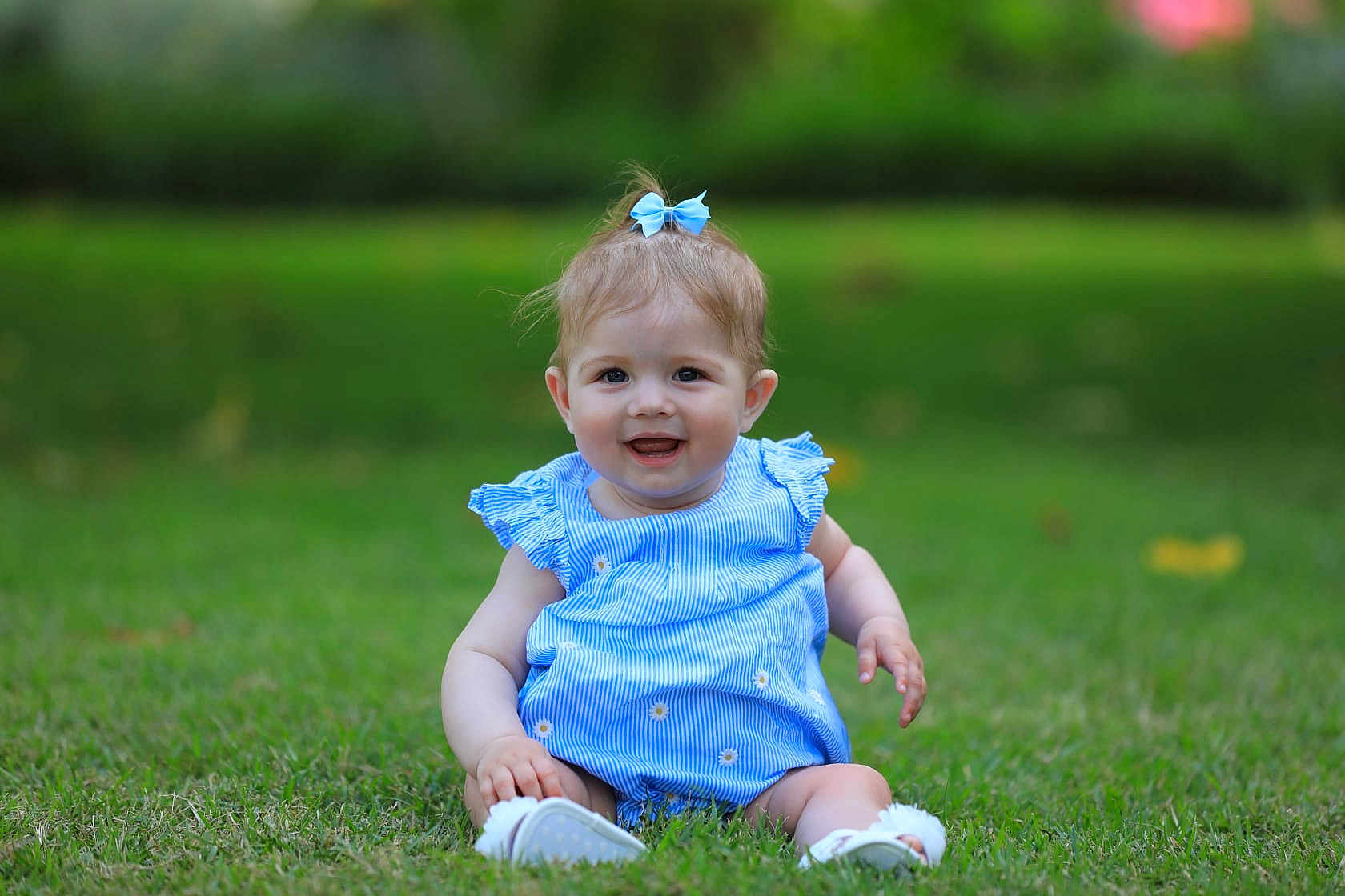 Ivy is registered to the contest to win money with this photo: baby, child, smiling, grass, blue_dress, bow, outdoor, nature, happy, sitting, infant, cute, portrait, young_child, greenery, sunlight, playful, summer, casual_clothing, barefoot