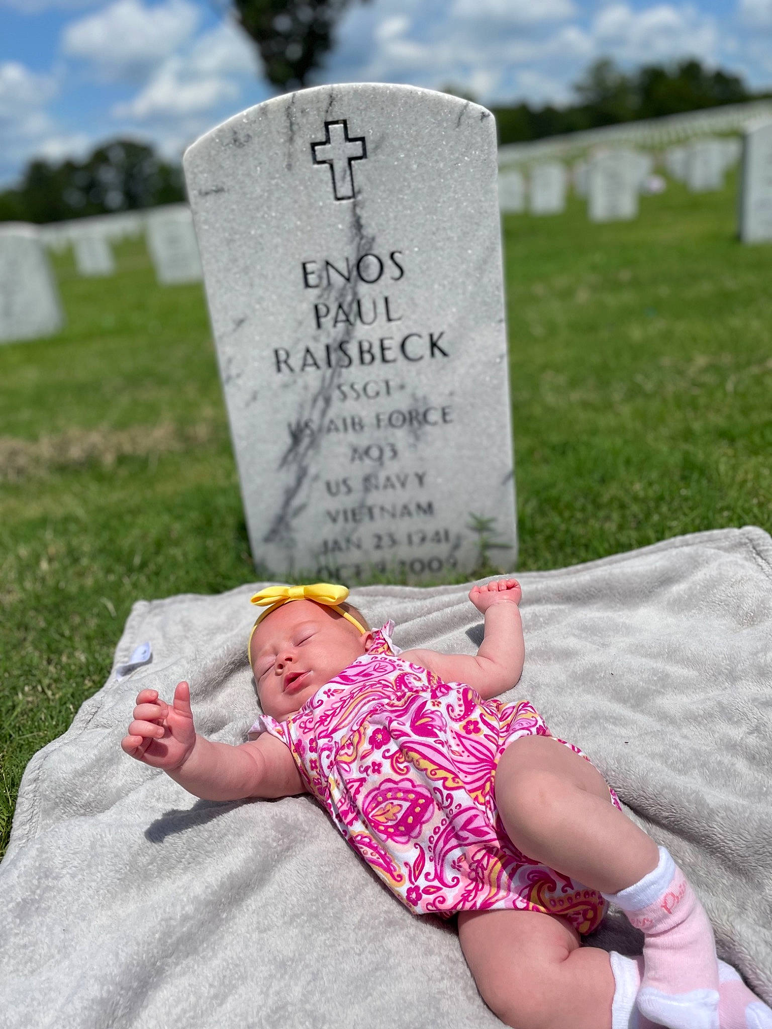 Lilah is registered to the contest to win money with this photo: baby_toddler_clothing, cemetery, cloud, comfort, font, grass, grass_family, grave, happy, headstone, leisure, people, people_in_nature, person, photograph, plant, sky, summer, toddler, tree