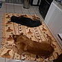 dog, animal, sleeping, indoor, kitchen, tile_floor, mat, appliance, stove, cabinet, brown_dog, black_and_brown_dog, resting, pet, domestic_animal, quiet, home, floor, cozy, relaxed