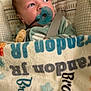 baby, pacifier, blanket, infant, child, face, blue, pattern, text, fabric, bed, cute, young, person, sleeping_bag, soft, closeup, wrapped, indoors, comfort