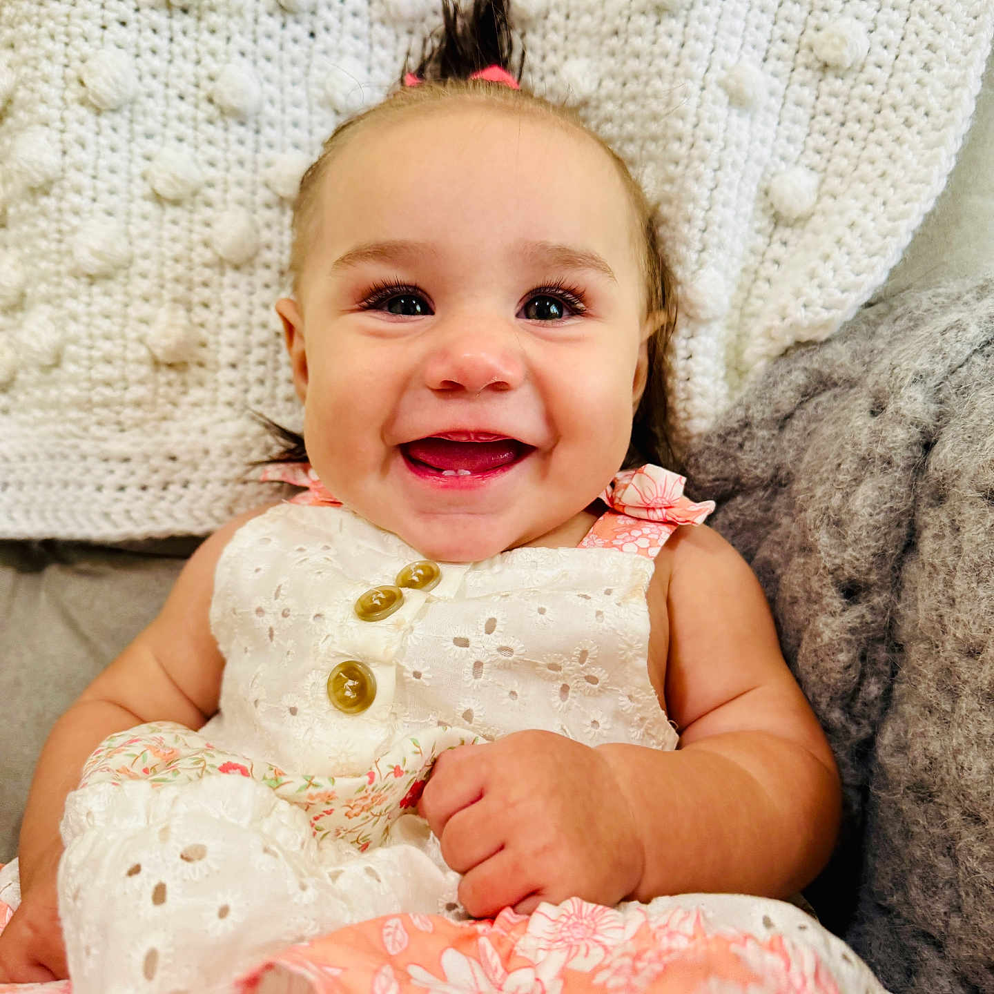 Rylee is registered to the contest to win money with this photo: baby, button, cheerful, child, cute, dress, eyelashes, fabric, face, hair, hand, happy, indoors, infant, knitted_blanket, person, portrait, seated, skin, smiling