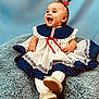 Rylee is registered to the contest to win money with this photo: baby, child, smiling, happy, dress, bow, hair, polka_dot, lace, white_tights, shoes, blanket, blue_background, sitting, portrait, cute, infant, indoors, child_fashion, joy