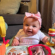 Poppy joined the competition — help win amazing prizes! baby, smiling, pink_headband, white_shirt, reflection, mirror, activity_center, toy, living_room, couch, cushion, lamp, curtains, child, infant, happy, indoors, person, play, cute