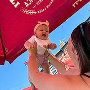 Poppy joined the competition — help win amazing prizes! accessory, arms, baby, bib, blue_sky, brick_building, child, clothing, daytime, happy, headband, holding, joy, outdoor, person, playful, smiling, sunlight, umbrella, woman