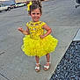 building, child, concrete, curly_hair, cute, daylight, dress, fashion, fire_department, girl, hair_accessory, happy, outdoor, pose, sandals, sidewalk, smiling, vehicle, yellow_dress, young