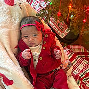 Vivianne is registered to the contest to win money with this photo: baby, infant, red_clothing, headband, blanket, christmas_tree, christmas_lights, plaid, floor, wood_floor, holiday, decorations, cute, indoors, person, newborn, festive, cozy, wrapped, relaxing