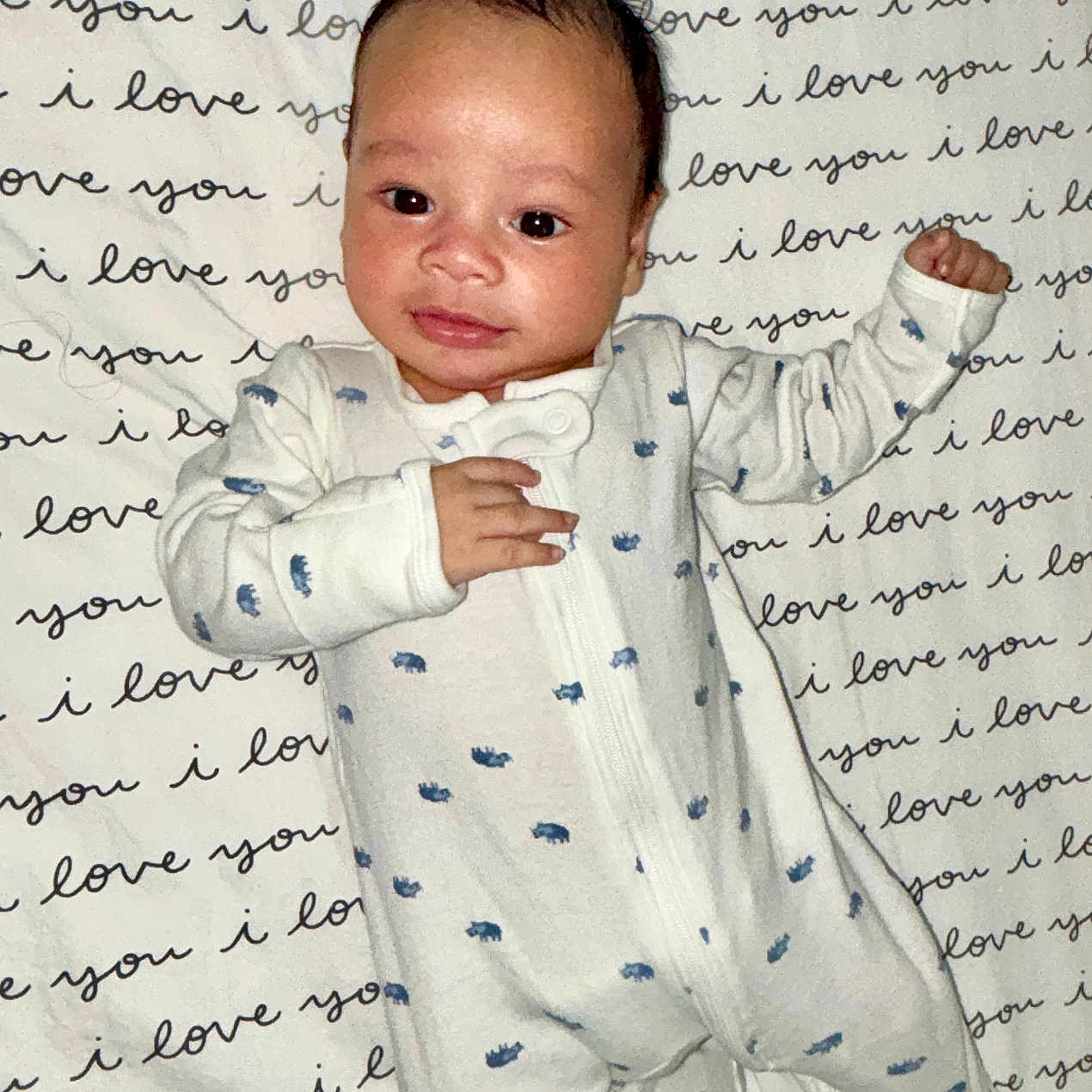 Noah is registered to the contest to win money with this photo: adorable, baby, blanket, child, closeup, cozy, cute, face, feet, hands, indoor, infant, love_message, lying_down, newborn, onesie, portrait, sleepwear, smiling, text_pattern