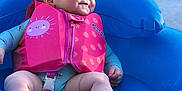 Kaliyah is registered to the contest to win money with this photo: baby, infant, life_jacket, float, water, blue, pink, smile, outdoor, child, cute, summer, sunshine, inflatable, sitting, young, happy, water_toy, playful, relaxing