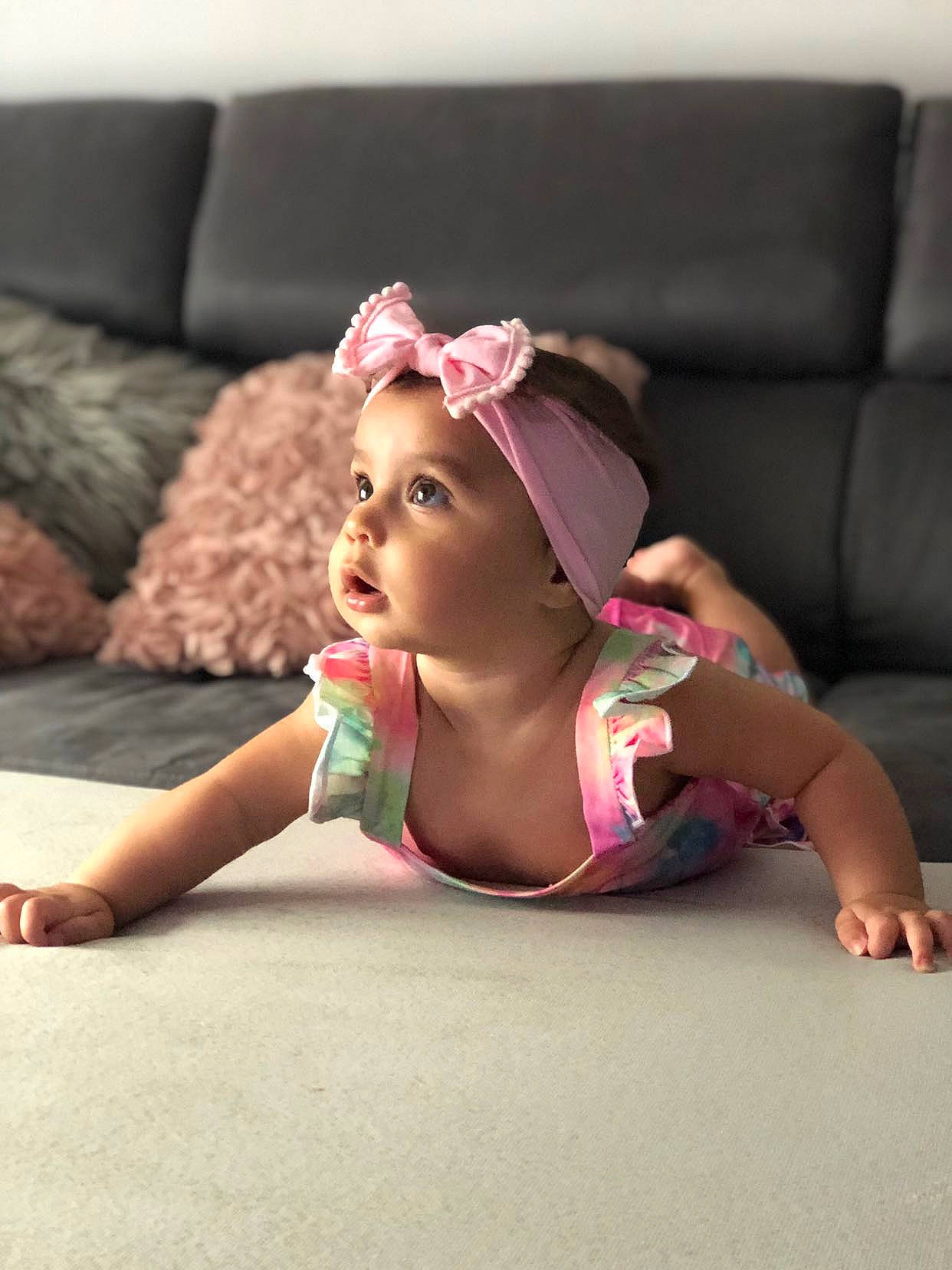 Irina participe au concours pour gagner de l'argent avec cette photo : baby_toddler_clothing, barefoot, comfort, costume_accessory, couch, elbow, finger, foot, hair_accessory, headband, headpiece, headwear, living_room, nail, person, pink, sitting, skin, toddler, toe
