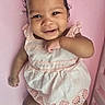 Arisbeth joined the competition — help win amazing prizes! baby, infant, smile, cute, pink_background, dress, clothing, face, happy, lying_down, skin, arm, hand, head, person, child, curly_hair, earring, footwear, indoors