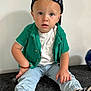 toddler, child, sitting, green_shirt, white_tshirt, blue_pants, black_cap, bracelet, sneakers, nike, indoor, curious, portrait, young_child, casual_clothing, black_and_white, expression, cute, fashion, person