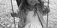 Léna a rejoint le concours — aidez-le/la à gagner de superbes lots ! child, girl, swing, playground, smiling, happy, curly_hair, outdoor, person, dress, jacket, ropes, seat, fun, leisure, nature, grass, adult, black_and_white, portrait