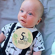Ethan a rejoint le concours — aidez-le/la à gagner de superbes lots ! baby, infant, 5_months, blue_eyes, mustache_pattern, black_suspender, white_shirt, wooden_milestone, lying_down, blanket, cute, child, portrait, soft_light, indoors, closeup, face, head, skin, expression