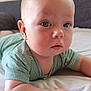 baby, child, infant, blue_eyes, mint_green_clothing, bed, blanket, skin, face, head, arms, fists, curious, indoors, soft_light, close_up, portrait, couch, resting, young