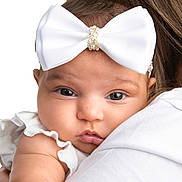 Kassie joined the competition — help win amazing prizes! baby, infant, child, white_bow, headband, close_up, portrait, face, skin, eyes, white_clothing, ruffles, shoulder, adult, person, cute, soft_skin, studio_lighting, isolated, expression